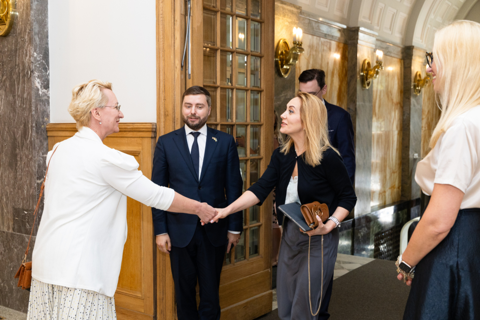Dace Melbārde spiež roku Olenai Homenko, blakus stāv Anatolijs Kucevols